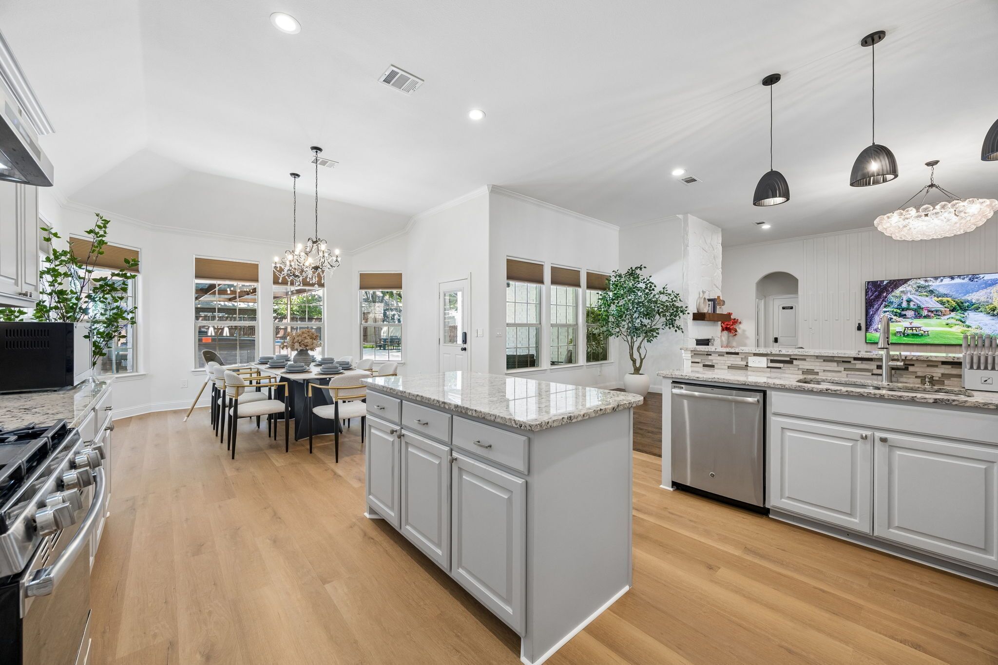 A modern kitchen with a central island, built-in appliances, and a dining area with a chandelier.