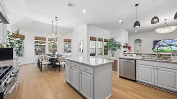 A modern kitchen with a central island, built-in appliances, and a dining area with a chandelier.