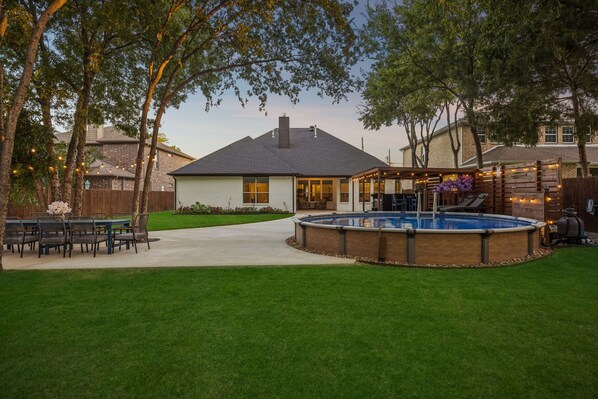A backyard with a swimming pool, a covered patio, and a dining area. - DFW retreat with pool, hot tub, and back yard oasis (Irving)