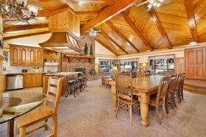 A spacious kitchen with wooden cabinets, a dining area with a large table and chairs, and a fireplace. - Bearfoot Lodge #2030 (Big Bear Lake)