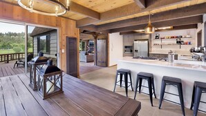 Una cocina moderna con una isla central, taburetes de bar y vistas al exterior.