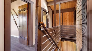Una escalera de madera con barandas de metal que conduce a una habitación con paredes de madera y techo inclinado.