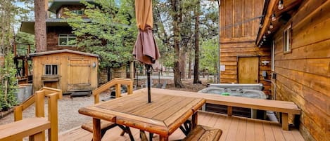 Eine Holzterrasse mit Picknicktischen und einem Whirlpool.
