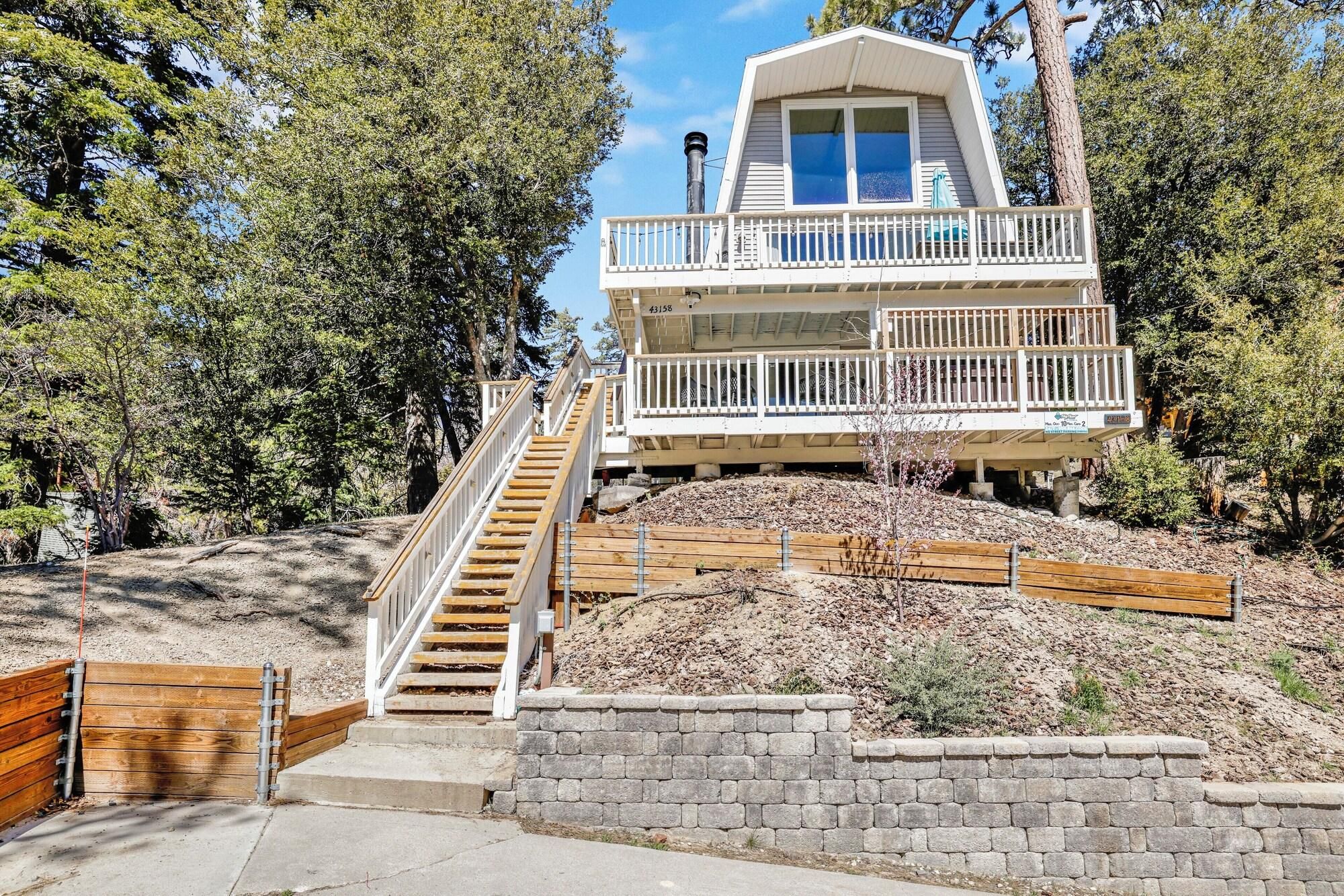 A two-story house with a balcony, a staircase leading to the entrance, and a stone retaining wall.