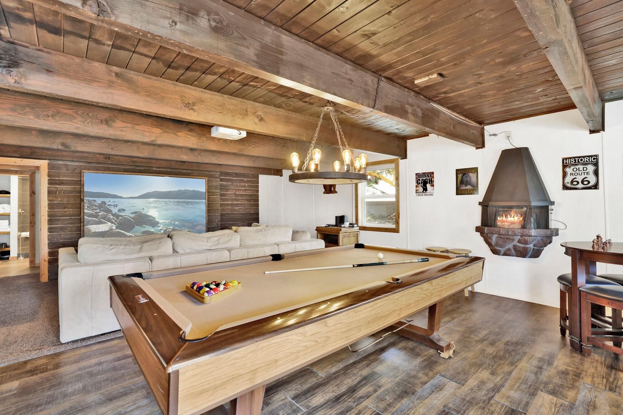 A wooden interior with a pool table, a sofa, and a fireplace.