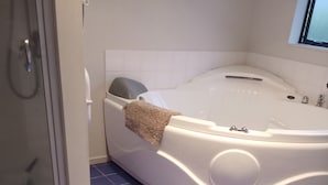 Ein Badezimmer mit einer Badewanne, einer Dusche und blau gefliestem Boden.