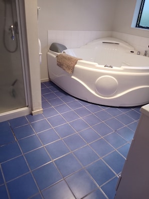 Ein Badezimmer mit einer Badewanne, einer Dusche und blau gefliestem Boden.
