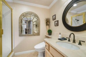A bathroom with a white toilet, a sink with a mirror, and a decorative arched mirror.