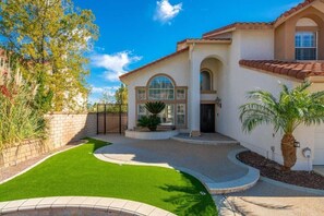A residential property with a well-maintained lawn, a curved driveway, and a large arched window.