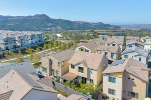 Una zona residencial con casas modernas, cielo despejado y montañas a lo lejos.