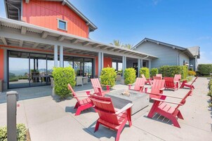 Un patio con sillones Adirondack rojos, una chimenea y vistas de una cordillera.