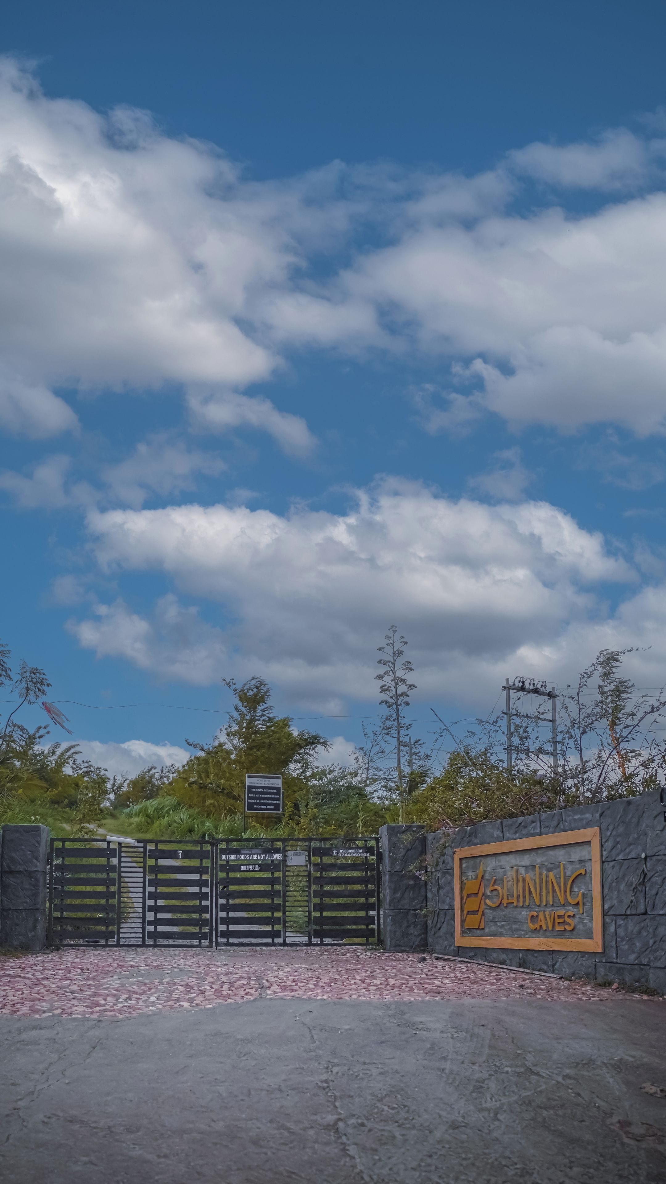 A gated entrance with a sign for 'Gaining Caves' and a warning about outside food.