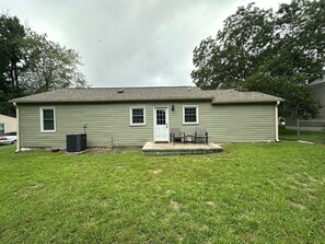 Einbungalow mit einer Veranda, einer Tür und einer kleinen angebauten Garage.
