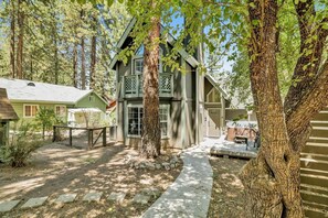 A rustic cabin with a porch, surrounded by trees and a gravel path. - Green Canoe Cabin #2293 (Big Bear Lake)