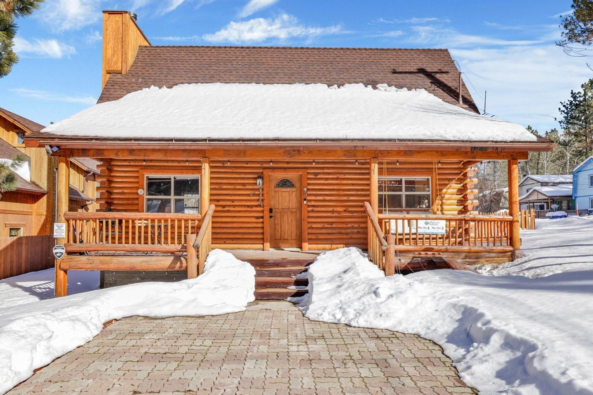 A wooden log cabin with a front porch and steps leading to the entrance.