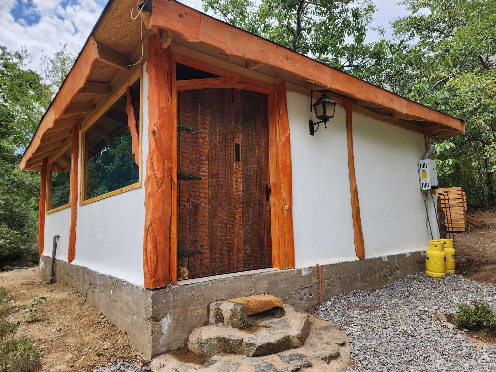 A small building with a wooden door, a window, and a light fixture.