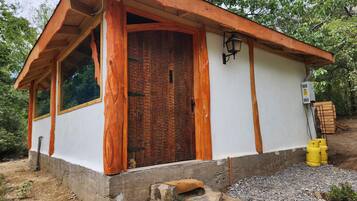 A small building with a wooden door, a window, and a light fixture.