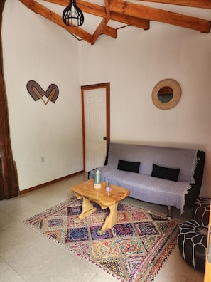 A cozy living room with a wooden ceiling, a patterned rug, a sofa, and a coffee table.
