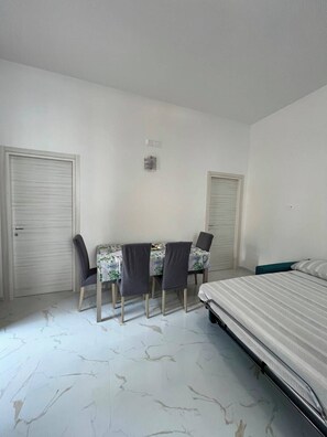 Ein Schlafzimmer mit einem Bett, einem Schreibtisch mit Stühlen und zwei Türen.