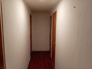 Un couloir étroit avec des portes en bois et un plancher rouge.