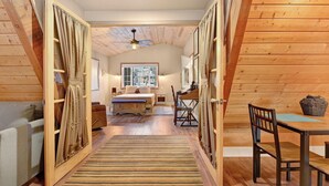 Un dormitorio acogedor en el ático, con techo de madera, una cama, un escritorio y una mesa de comedor.