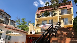 Un hotel con piscina, mobiliario exterior y una escalera que lleva a la entrada.