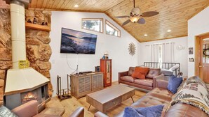 Una sala acogedora con chimenea, sofás de cuero, un televisor y una pared de piedra.