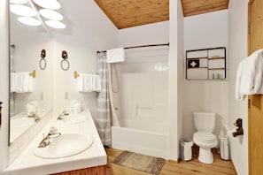 Une salle de bain avec deux lavabos, une douche, des toilettes et un miroir avec un porte-serviettes.
