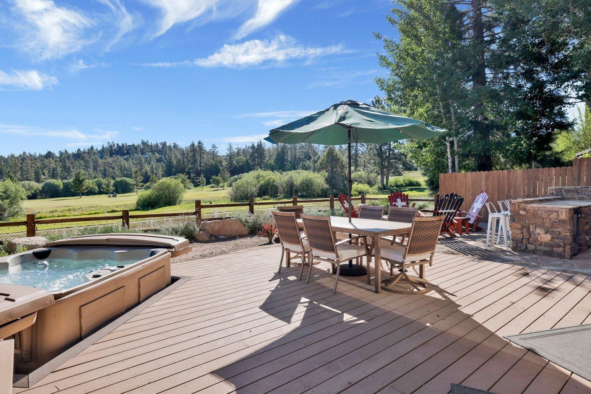 Um terraço com hidromassagem, área de estar externa e vista para um campo de golfe.
