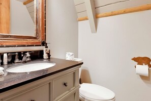 A bathroom with a wooden vanity, two sinks, a mirror, and a toilet. - Big Bear Den #2152 (Big Bear Lake)