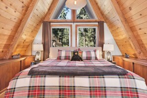 A bedroom with a bed, two bedside lamps, and a window with a view of trees. - Big Bear Den #2152 (Big Bear Lake)