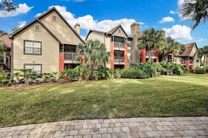 A row of two-story residential buildings with balconies, surrounded by well-maintained lawns and tropical plants. - Landing Jacksonville (Jacksonville)