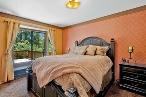 A bedroom with a large bed, a nightstand, a dresser, and a window with curtains. - Club View Pines #2105 (Big Bear Lake)