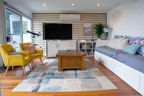 A modern living room with a flat-screen TV, yellow armchairs, a wooden coffee table, and a grey sofa with patterned cushions. - Coastal 3-Bed Haven With Panoramic Views (Portarlington)
