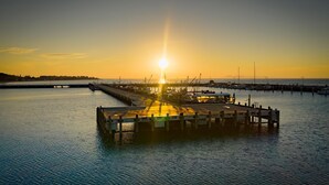 A pier extending into calm water with a sunset in the background. - Coastal 3-Bed Haven With Panoramic Views (Portarlington)