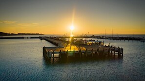 A pier extending into calm water with a sunset in the background. - Coastal 3-Bed Haven With Panoramic Views (Portarlington)