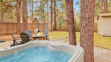 A backyard with a hot tub, outdoor seating, and a wooden deck.