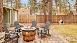 A patio with four Adirondack chairs, a round wooden barrel, and a fire pit. - Beary Cozy Cabin #2315 (Big Bear Lake)