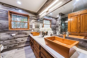 A bathroom with a large mirror, wooden vanity, and a marble backsplash. - Bears Palace Chalet #2008 (Big Bear Lake)