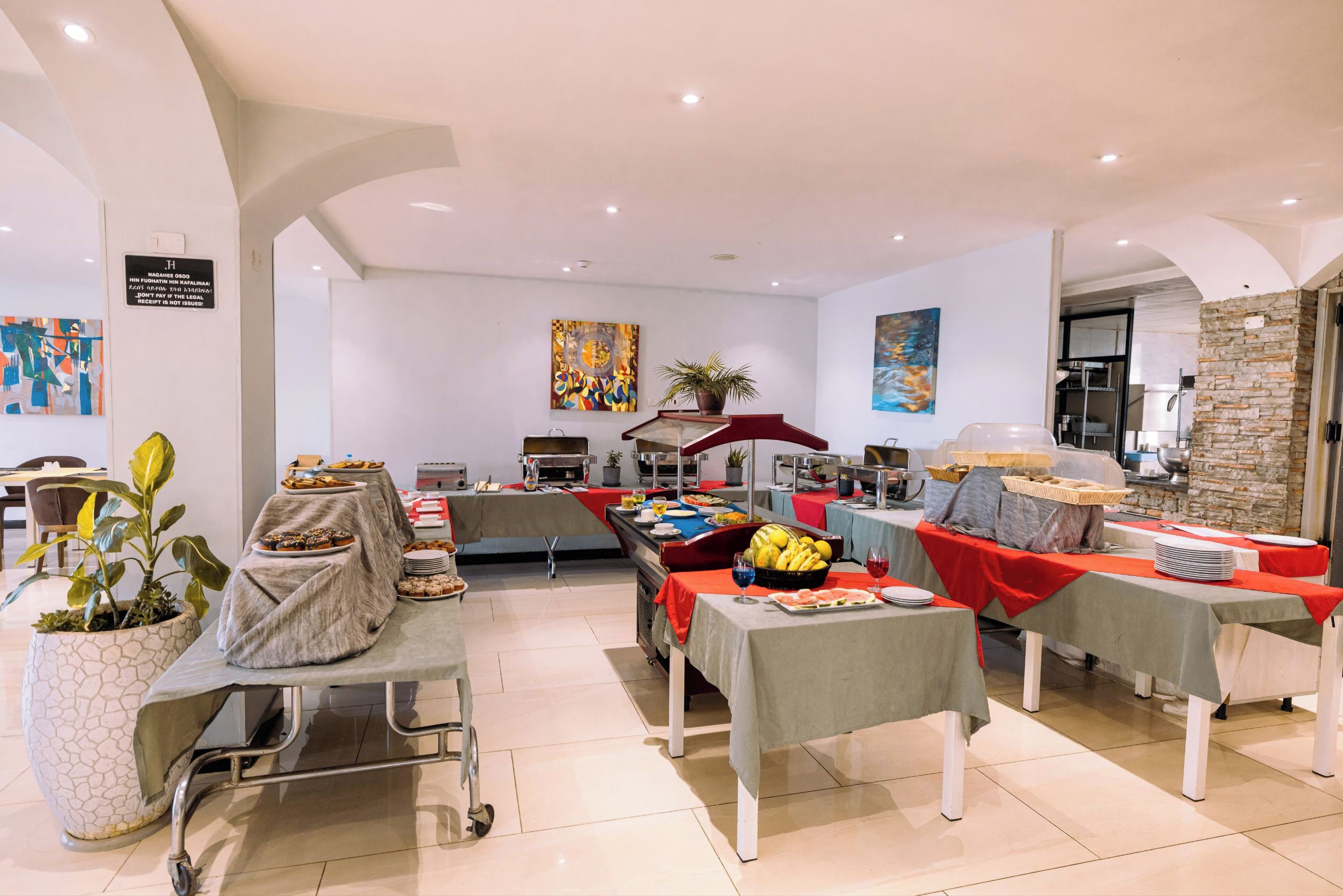 A spacious room with a buffet setup, a wheelchair, and a potted plant.