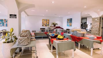 A spacious room with a buffet setup, a wheelchair, and a potted plant.