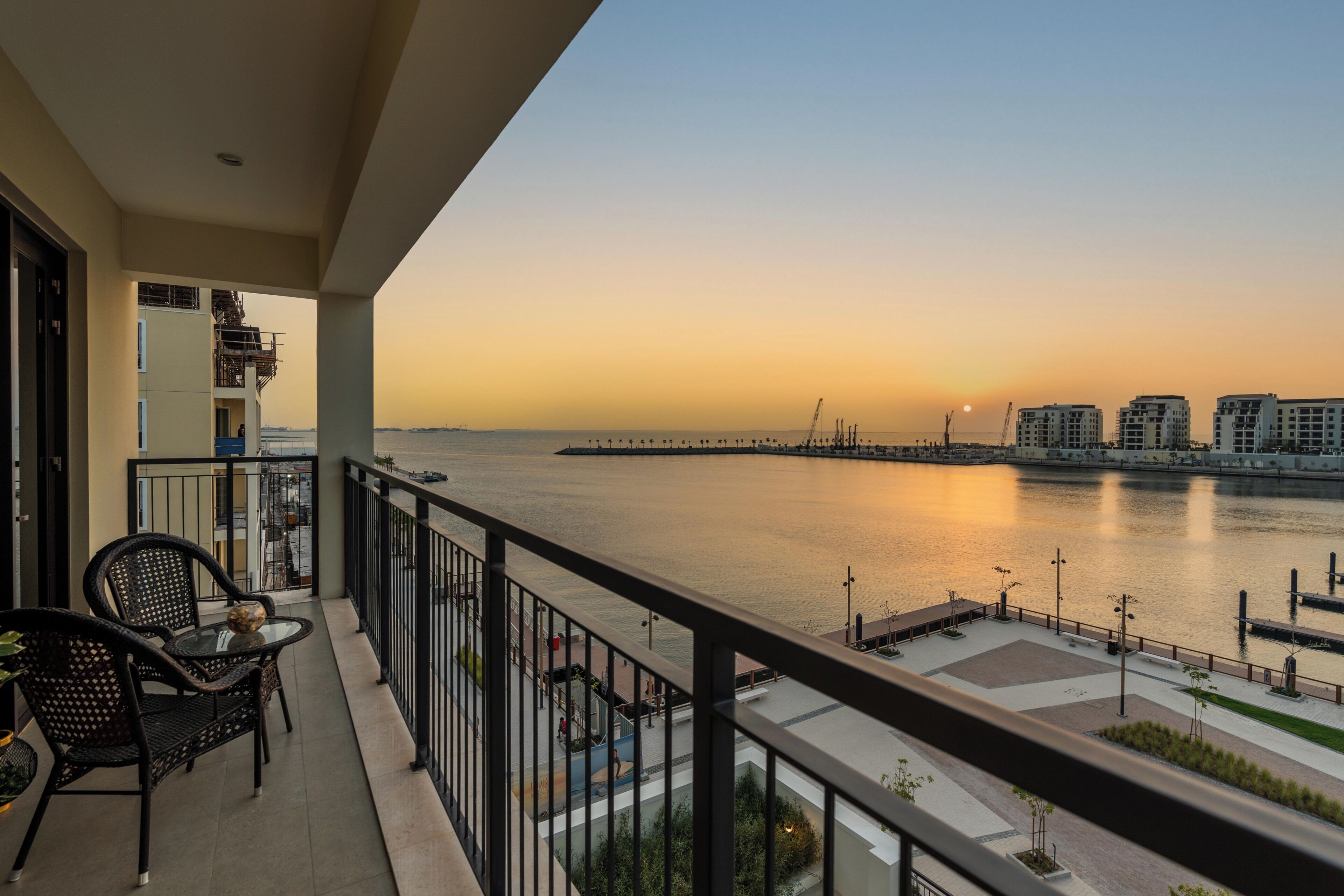Ein Balkon mit Blick auf ruhiges Wasser, eine ferne Stadtlandschaft und einen klaren Himmel.