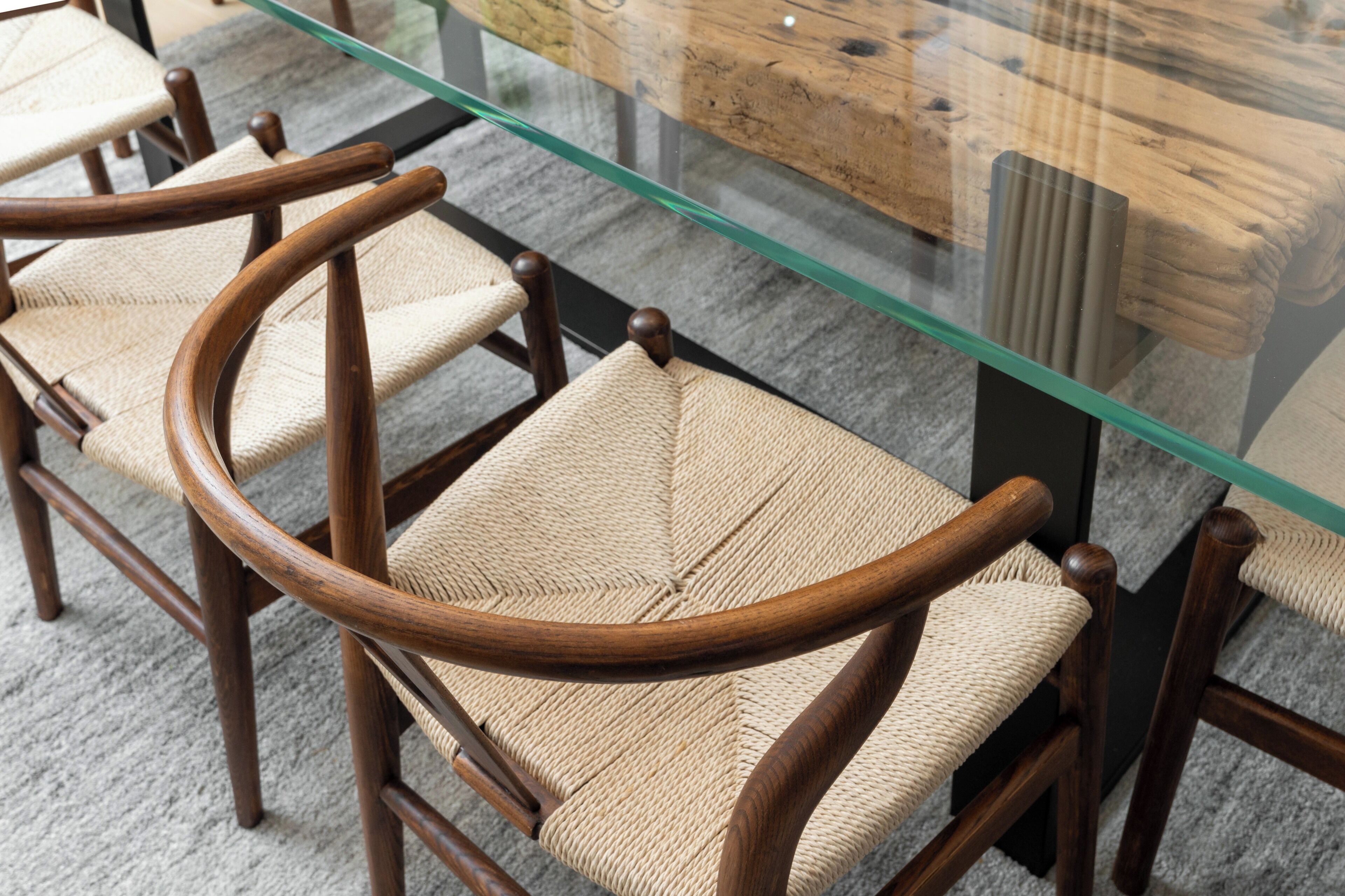 A glass-top table with wooden chairs with woven seats.