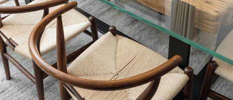 A glass-top table with wooden chairs with woven seats.