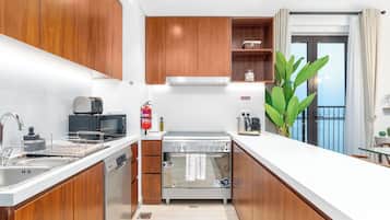 Eine moderne Küche mit Holzausstattung, Edelstahlgeräten und Meerblick vom Balkon.