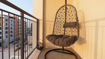 Ein Balkon mit Hängesessel, Laterne und Blick auf Gebäude.