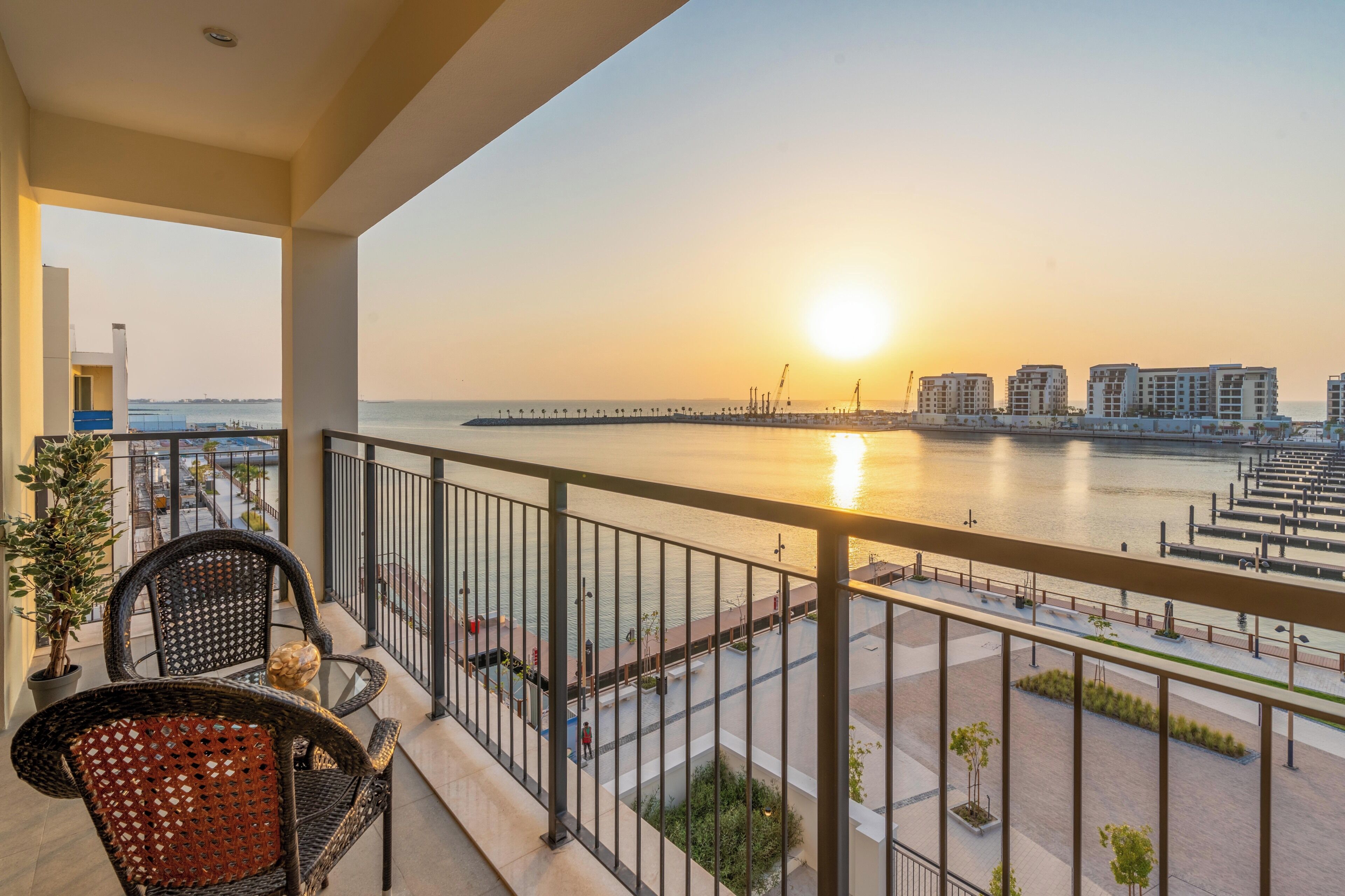 Un balcon avec vue sur la mer et un quai, agrémenté de mobilier d’extérieur et d’une balustrade.
