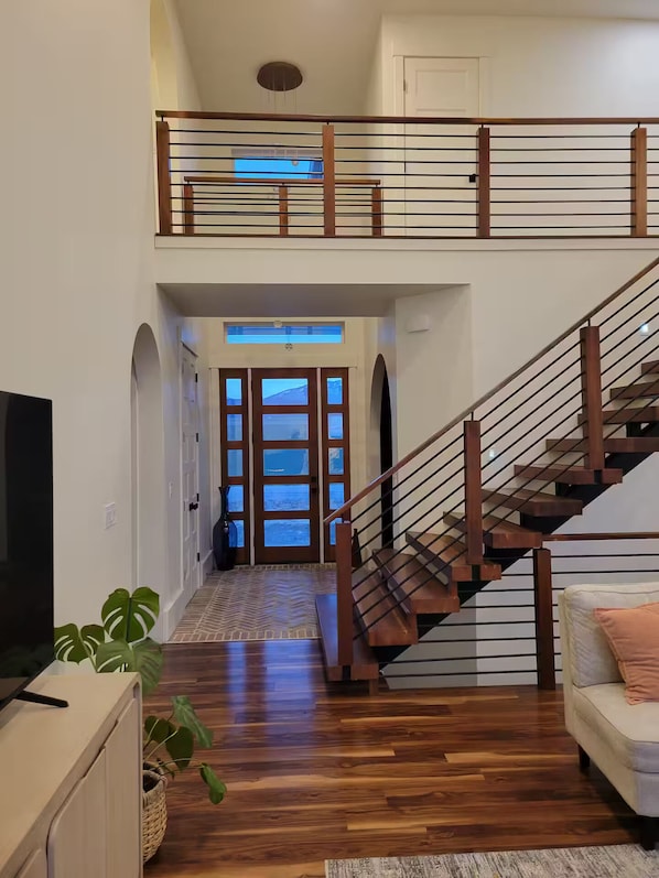 Amplia sala de estar con escalera de madera, televisor de pantalla plana y sofá.