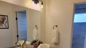 Casa de banho com lavatório duplo, espelho e vista para uma varanda.