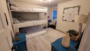 Quarto com beliche, escrivaninha, luminária e janela com vista.